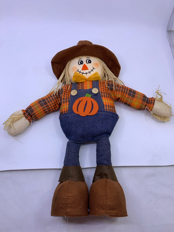 STANDING SCARECROW IN ORANGE SHIRT JEANS OVERALLS.