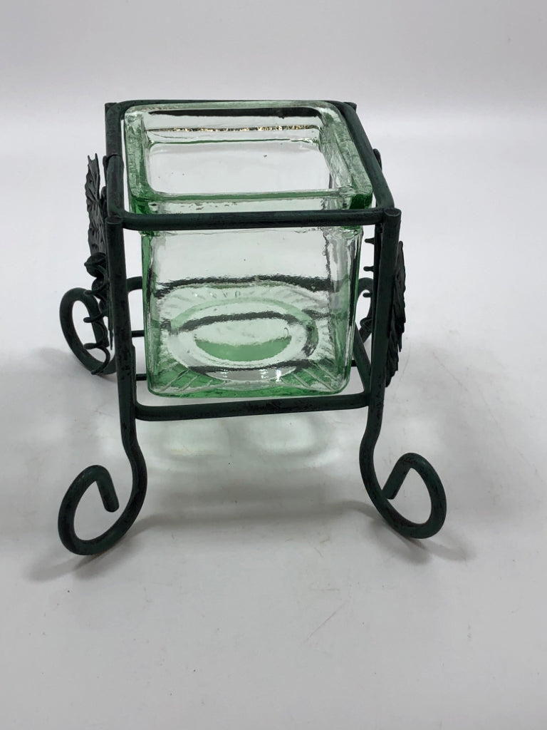 GREEN GLASS VOTIVE HOLDER IN GREEN METAL STAND.