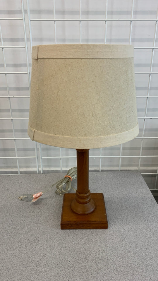 WOOD BASE TABLE LAMP W/TAN SHADE.
