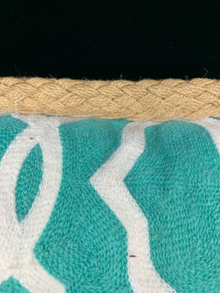 TEAL PILLOW W/WHITE DESIGN & BRAIDED BURLAP BORDER.