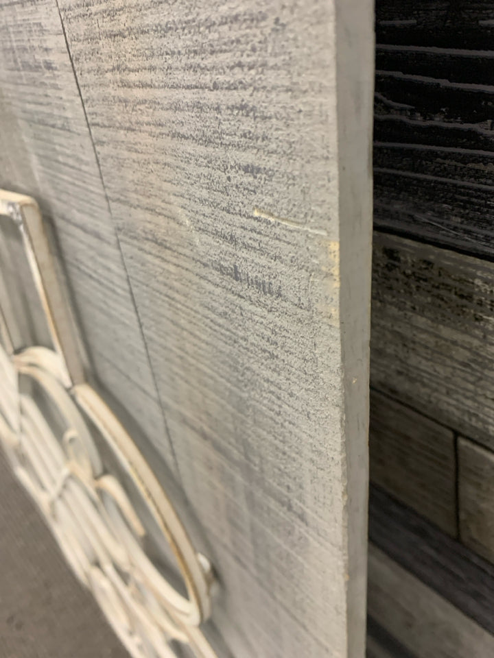 WHITE METAL MEDALLION ON GREY WOOD WALL DECOR.