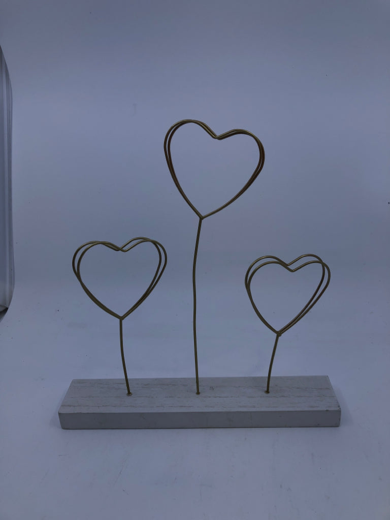 GOLD METAL HEART PHOTO HOLDER ON WHITE WOOD BLOCK.