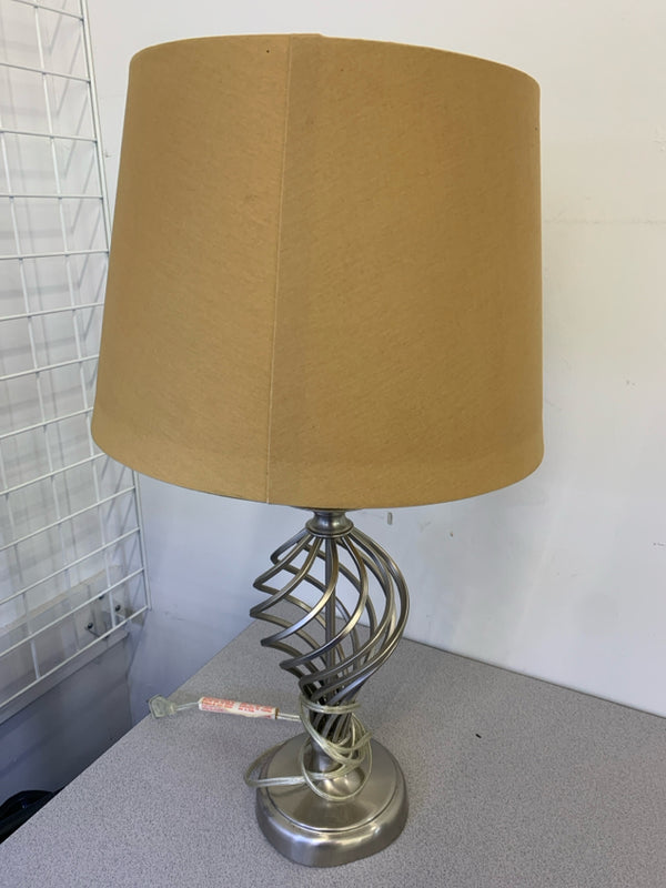 SILVER SWIRL TABLE LAMP WITH TAN SHADE.