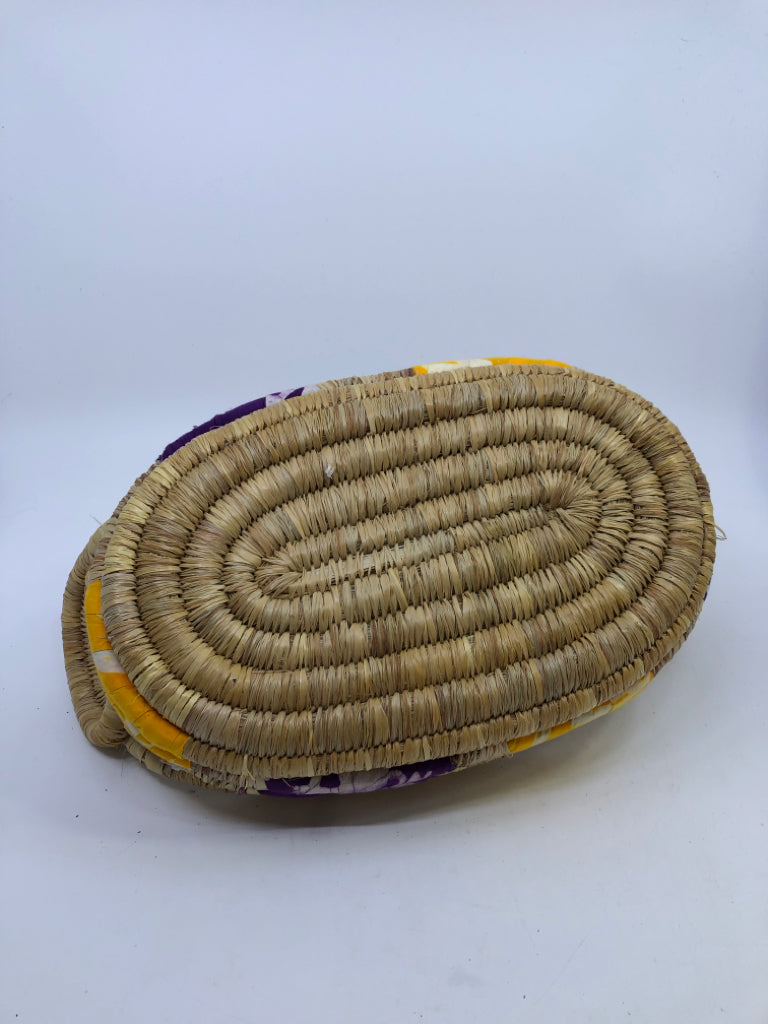 SWIRLED WICKER BASKET W/YELLOW AND PURPLE CLOTH & HANDLES.