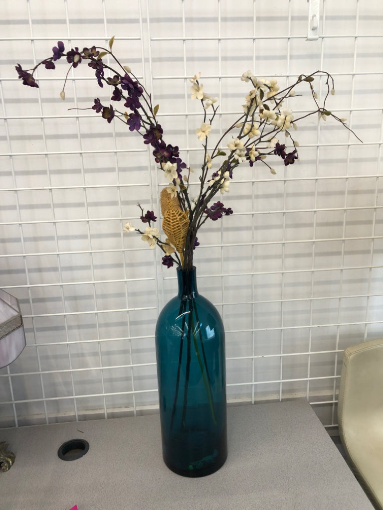 PURPLE FLORALS IN BLUE GLASS VASE.