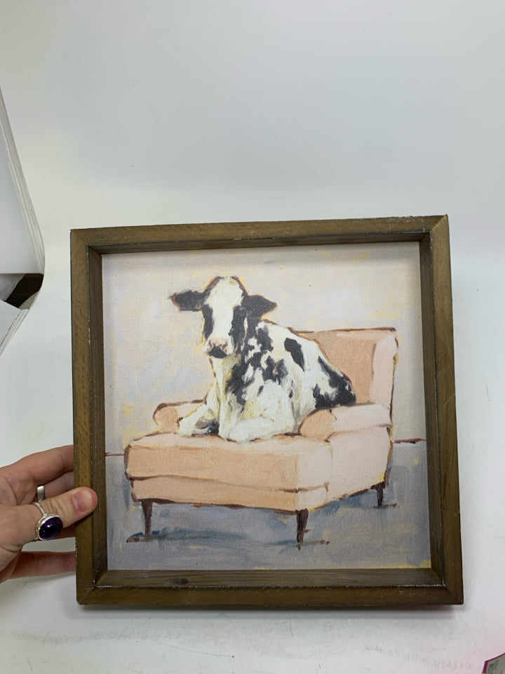 COW ON PINK COUCH IN WOOD FRAME WALL HANGING.