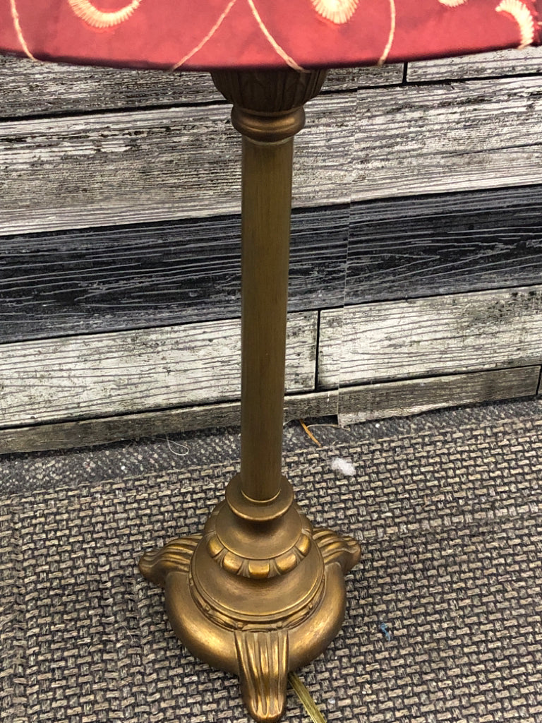 GOLD COLORED METAL DISTRESSED LAMP W/ RED SCROLL SHADE.