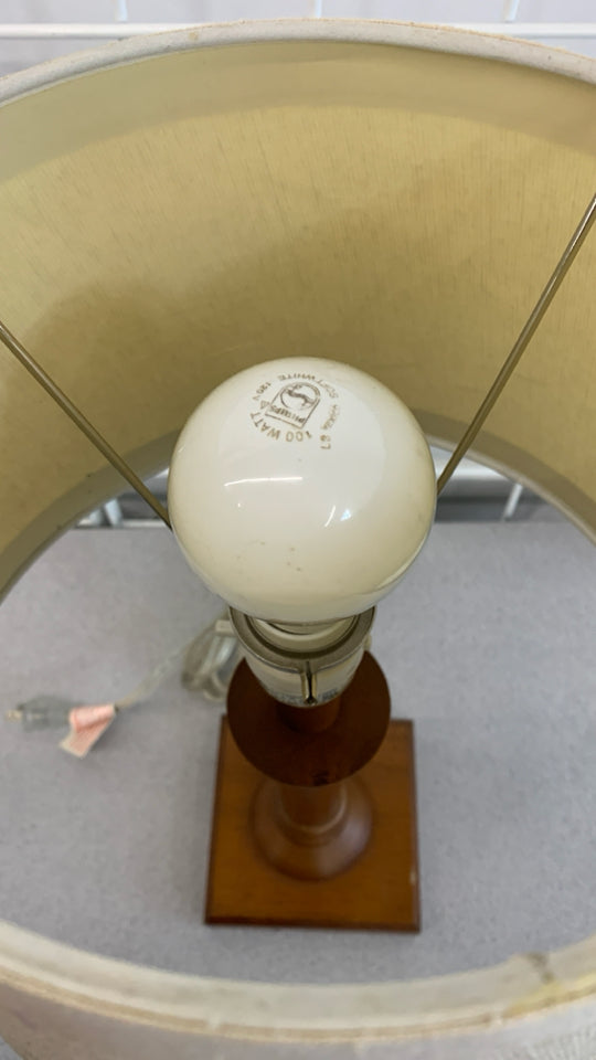 WOOD BASE TABLE LAMP W/TAN SHADE.