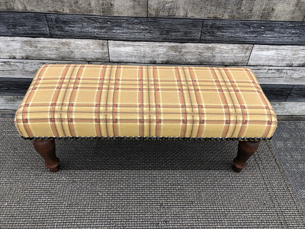 PLAID FOOTSTOOL W/DARK WOOD LEGS.