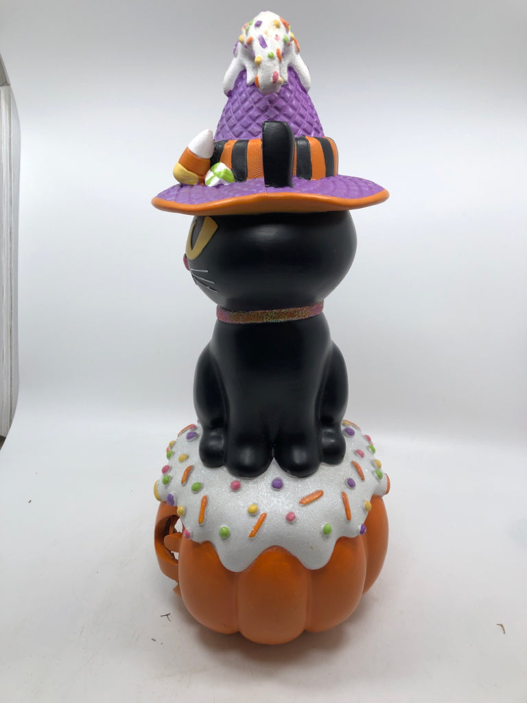 BLACK CAT W/ CANDY HAT SITTING ON LIGHT UP JACKO LANTERN.
