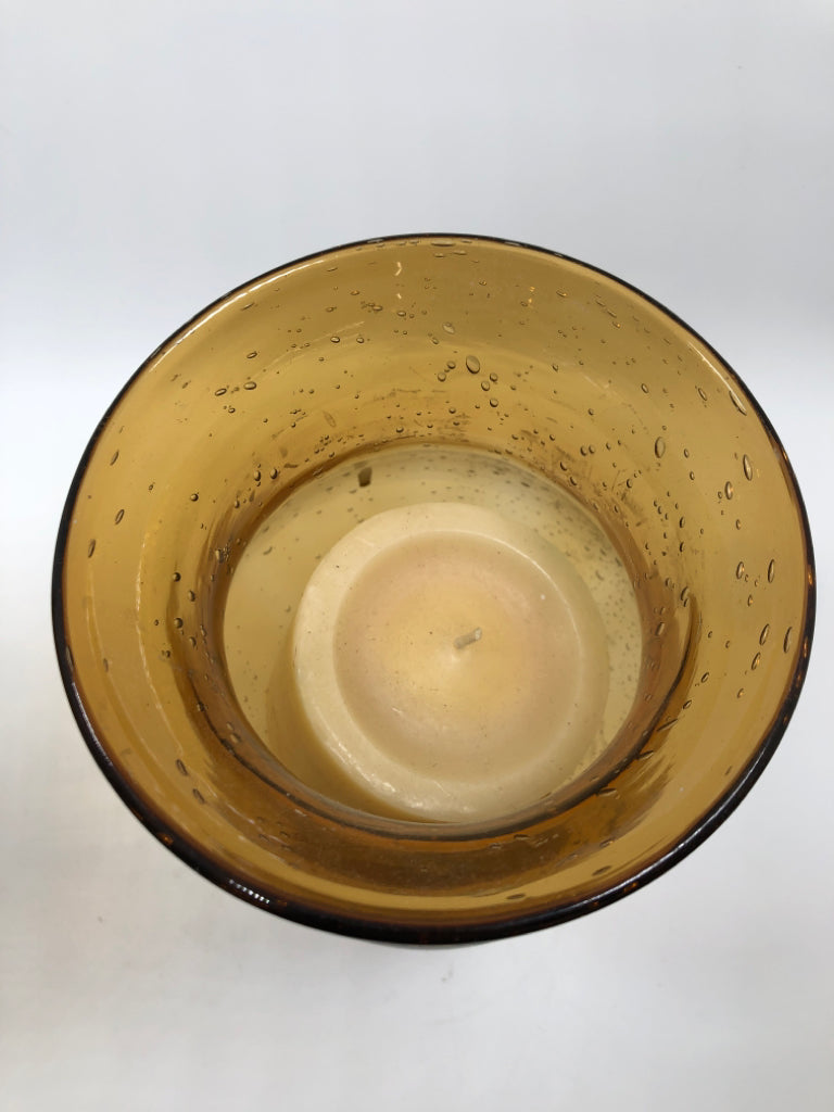 2 AMBER GLASS CANDLE HOLDERS W/WAX CANDLES.