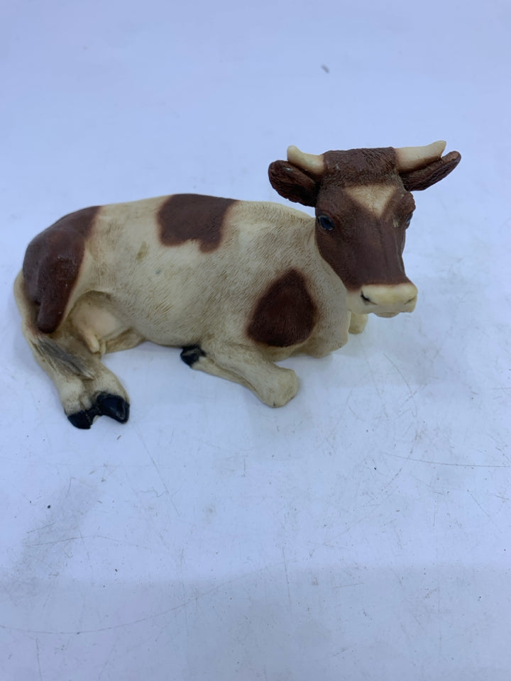 BROWN/WHITE COW LAYING.