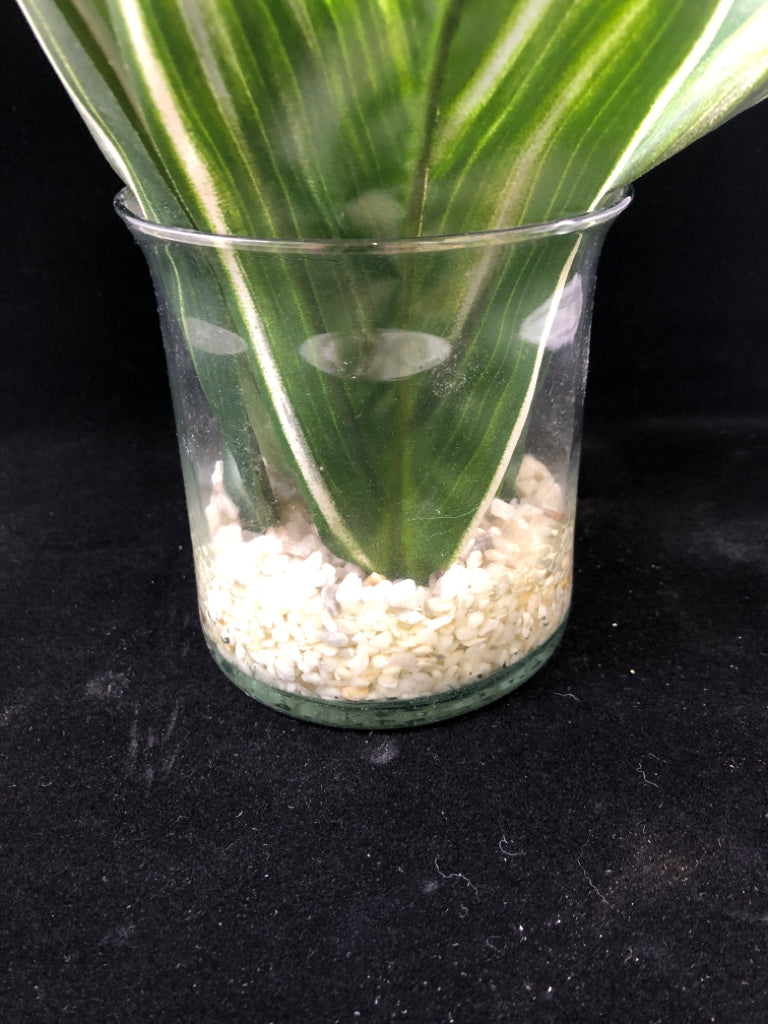 FAUX LEAVES W/ WHITE FLOWERS IN CLEAR VASE W/ WHITE ROCKS.