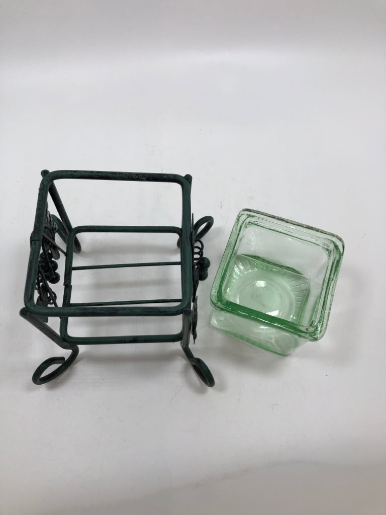 GREEN GLASS VOTIVE HOLDER IN GREEN METAL STAND.