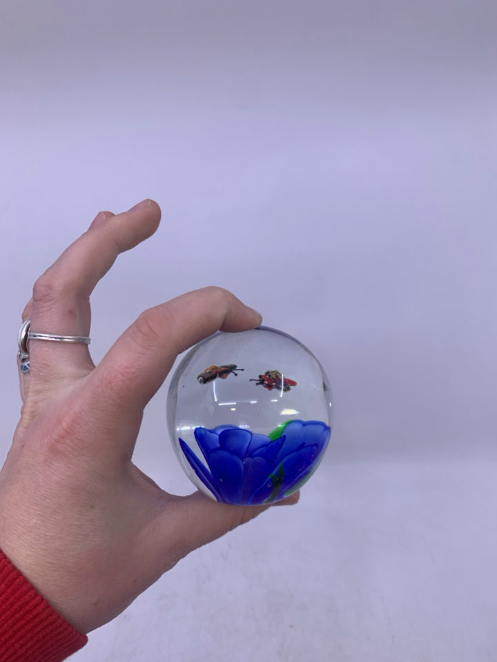 BLOWN GLASS SPHERE W/ BLUE FLOWER BEES FLYING ABOVE IT.