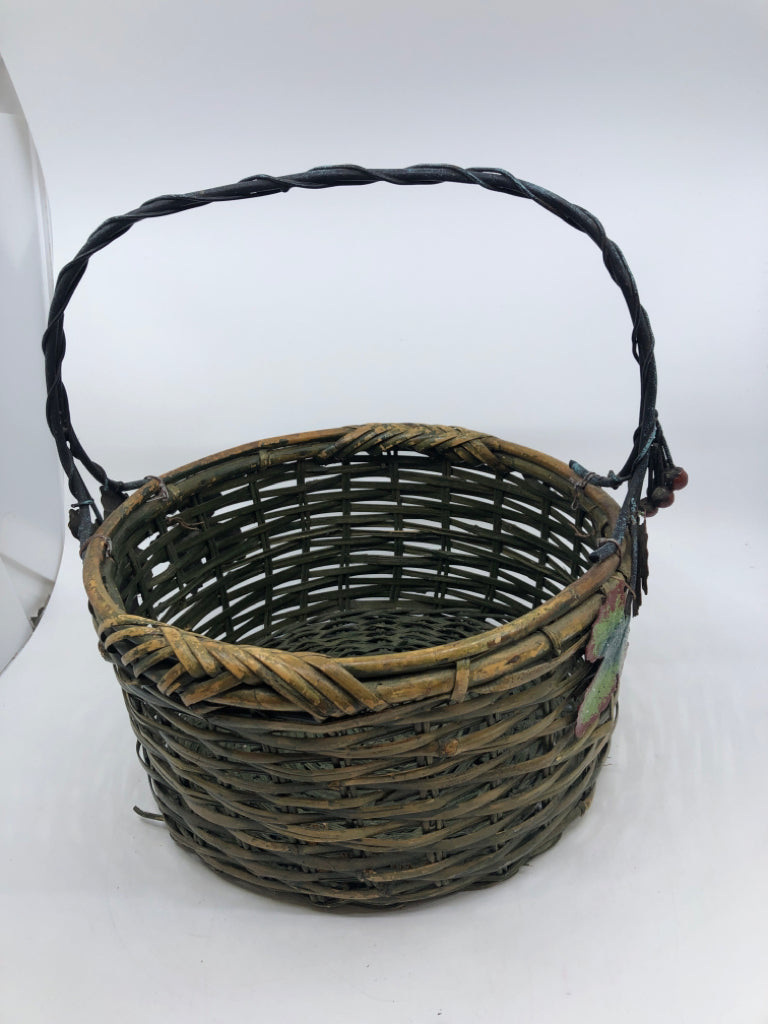GREEN WOVEN BASKET W METAL HANDLE AND LEAVES.
