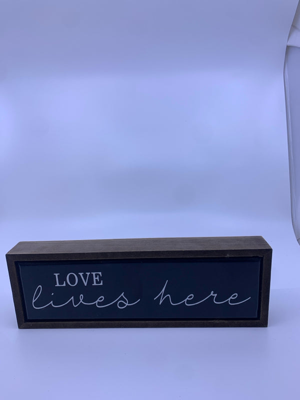 "LOVE LIVES HERE" BLACK W/ WHITE LETTERS WALL ART.