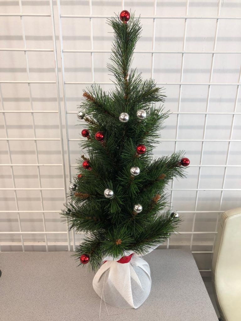 FAUX TREE W/RED WHITE ORNAMENTS IN WHITE BURLAP BASE.