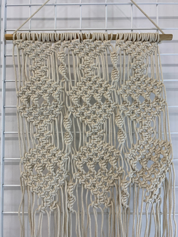 CREAM MACRAME WALL HANGING ON DOWEL ROD.