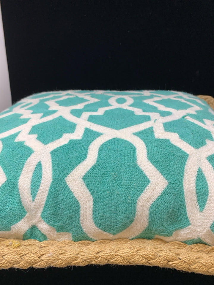 TEAL PILLOW W/WHITE DESIGN & BRAIDED BURLAP BORDER.