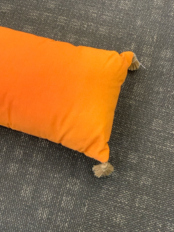 ORANGE RECTANGLE PILLOW WITH TASSELS.