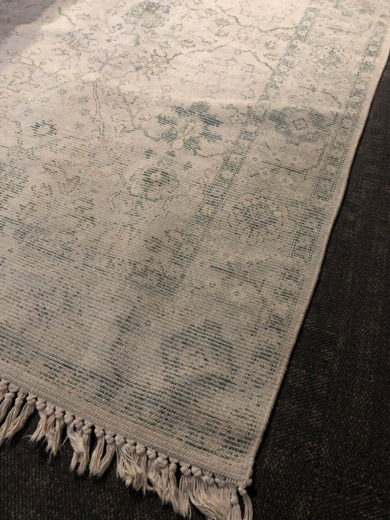 CREAM RUG W/ FADED LOOK GREEN PATTERN W/ TASSELS.