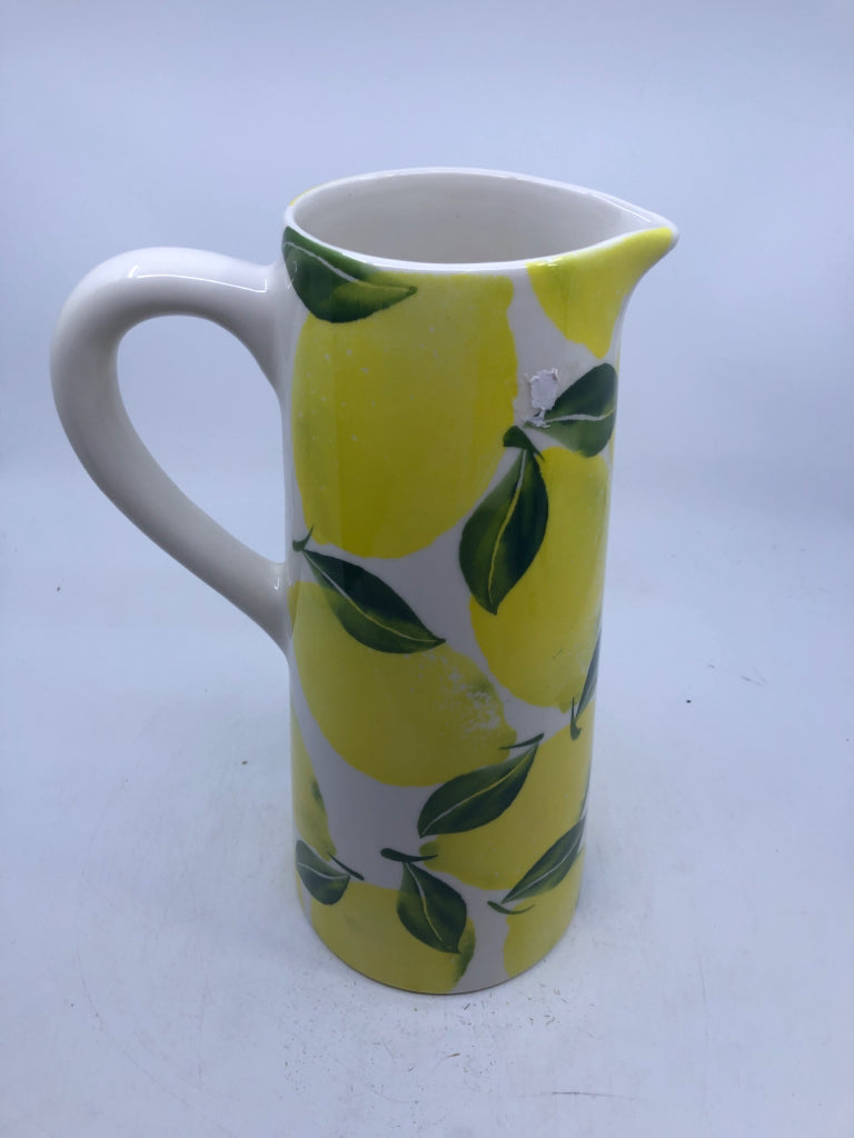 TALL WHITE CERAMIC PITCHER WITH LEMONS.