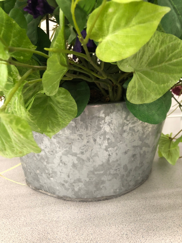 FAUX PURPLE FLOWERS IN GALVANIZED TIN WALL POCKET.