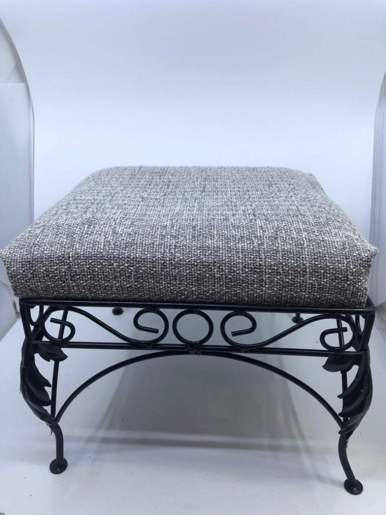 GREY FABRIC FOOTSTOOL W/BLACK IRON SCROLL LEGS.