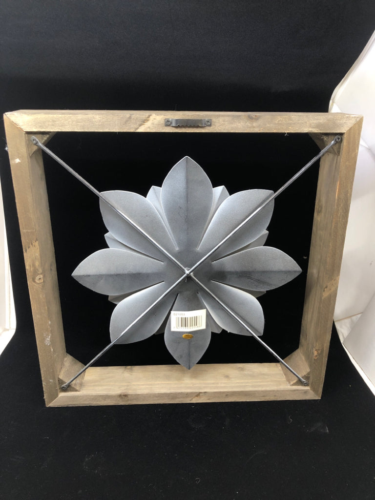 WHITE METAL FLOWER SUSPENDED IN WOOD FRAME.