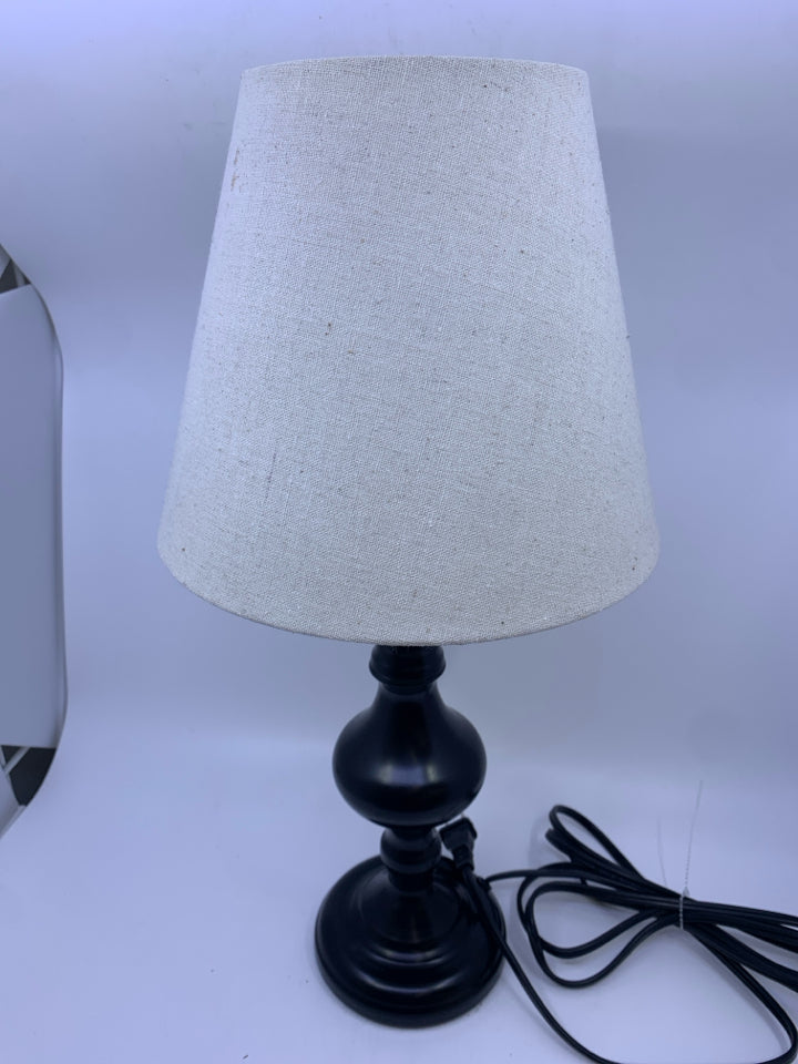 BLACK BASE TAP LAMP W/ 3 SETTINGS AND A CREAM SHADE.