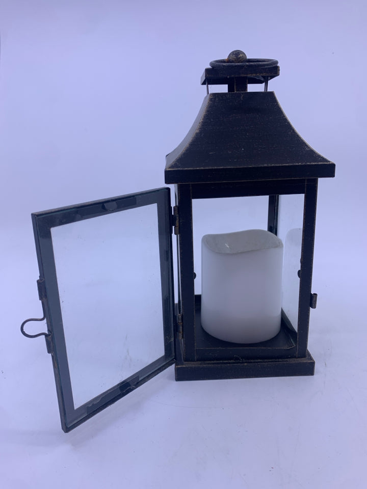 BLACK DISTRESSED LANTERN WITH ELECTRIC WHITE CANDLE.