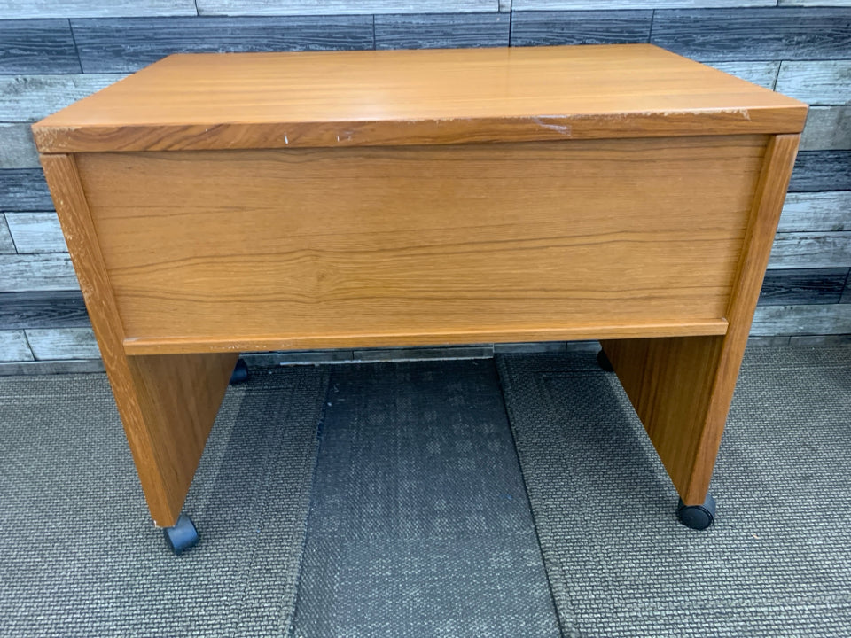 SMALL HEAVY WOOD DESK ON WHEELS W/ INSIDE SHELF.