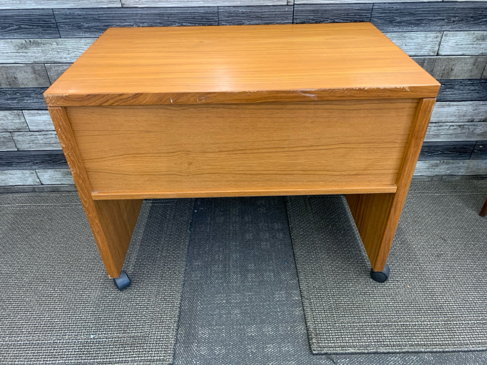 SMALL HEAVY WOOD DESK ON WHEELS W/ INSIDE SHELF.