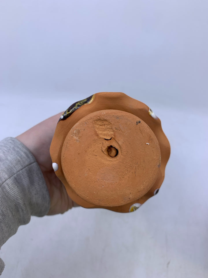 CLAY FACELESS WOMAN BROWN HAT HOLDING PINK FLOWERS.