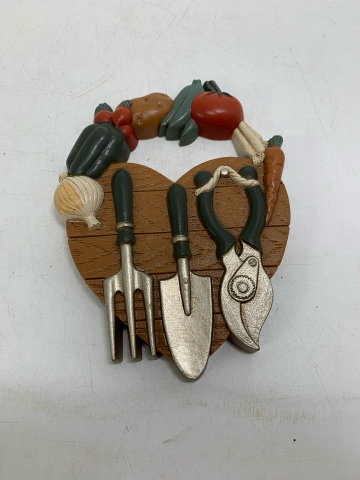SMALL VTG PLASTIC HEART SHAPED PLAQUE W/ VEGGIES & GARDEN TOOLS.