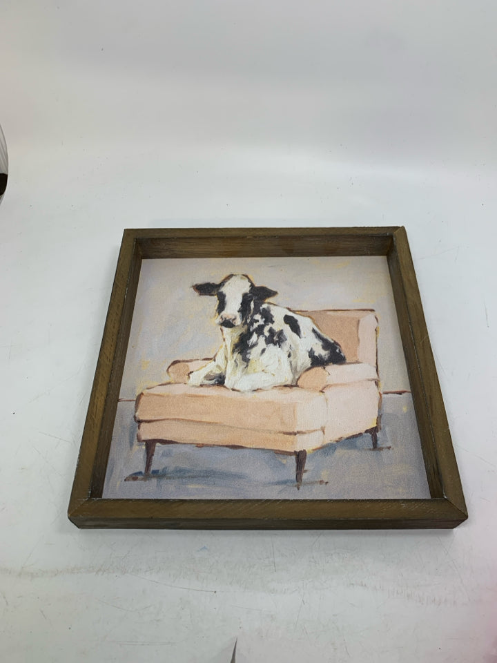 COW ON PINK COUCH IN WOOD FRAME WALL HANGING.