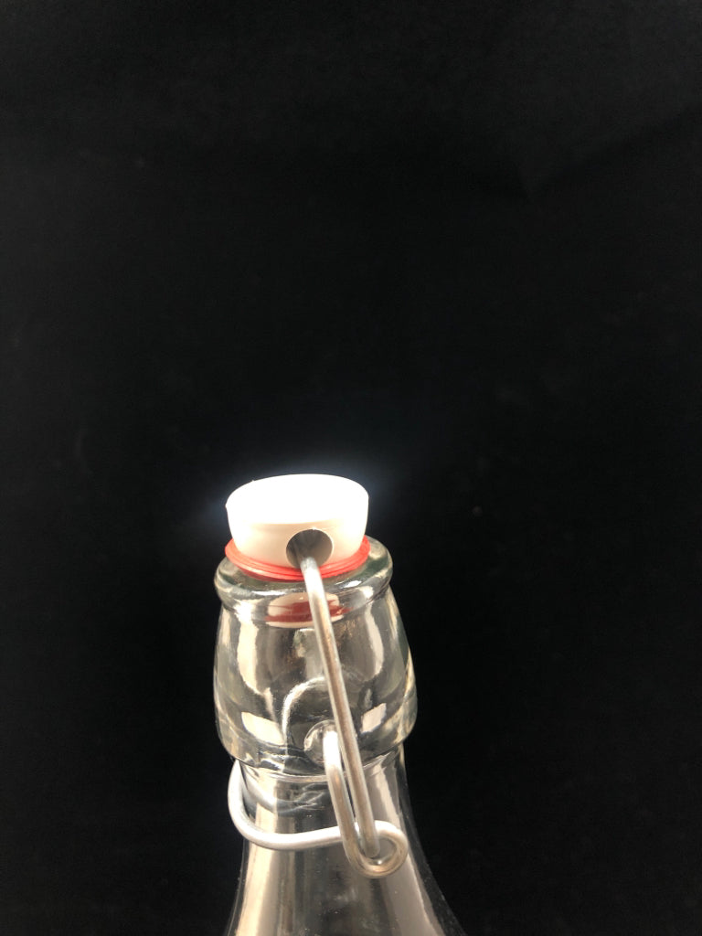CLEAR GLASS BOTTLE W/FLIP TOP STOPPER.