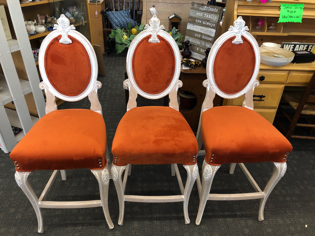 3 BURNT ORANGE UPHOLSTERED WHITE WASHED BAR STOOLS W/ FLORAL DESIGN ON BACK.