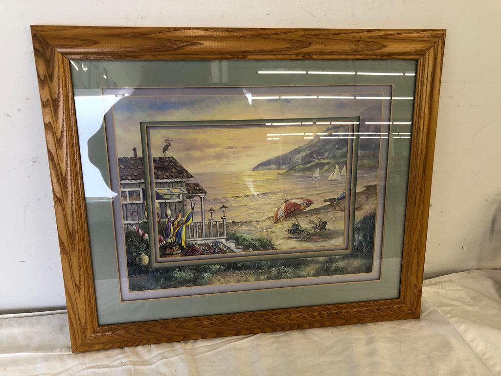 PEOPLE SITTING UNDER UMBRELLA BY THE BEACH WALL ART IN WOOD FRAME.