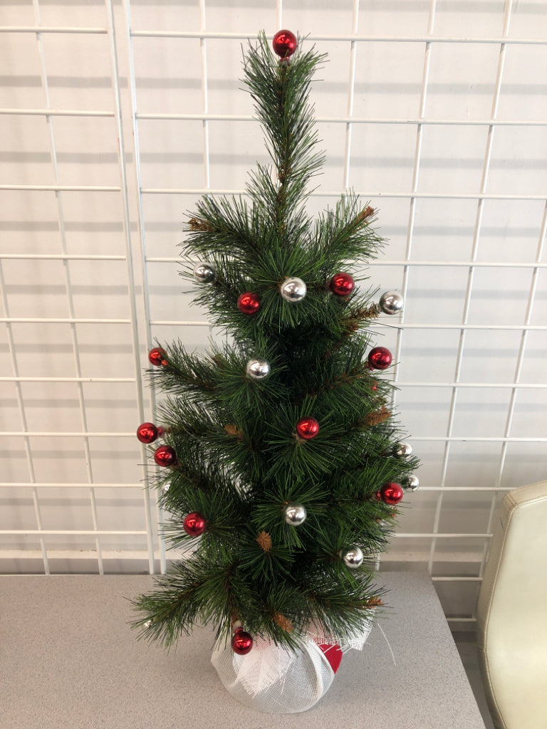 FAUX TREE W/RED WHITE ORNAMENTS IN WHITE BURLAP BASE.