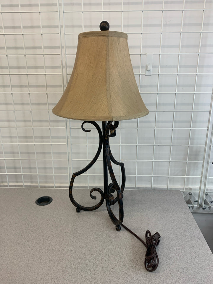 BLACK SCROLL BASE LAMP W/GOLD FLECKS AND TAN SHADE.