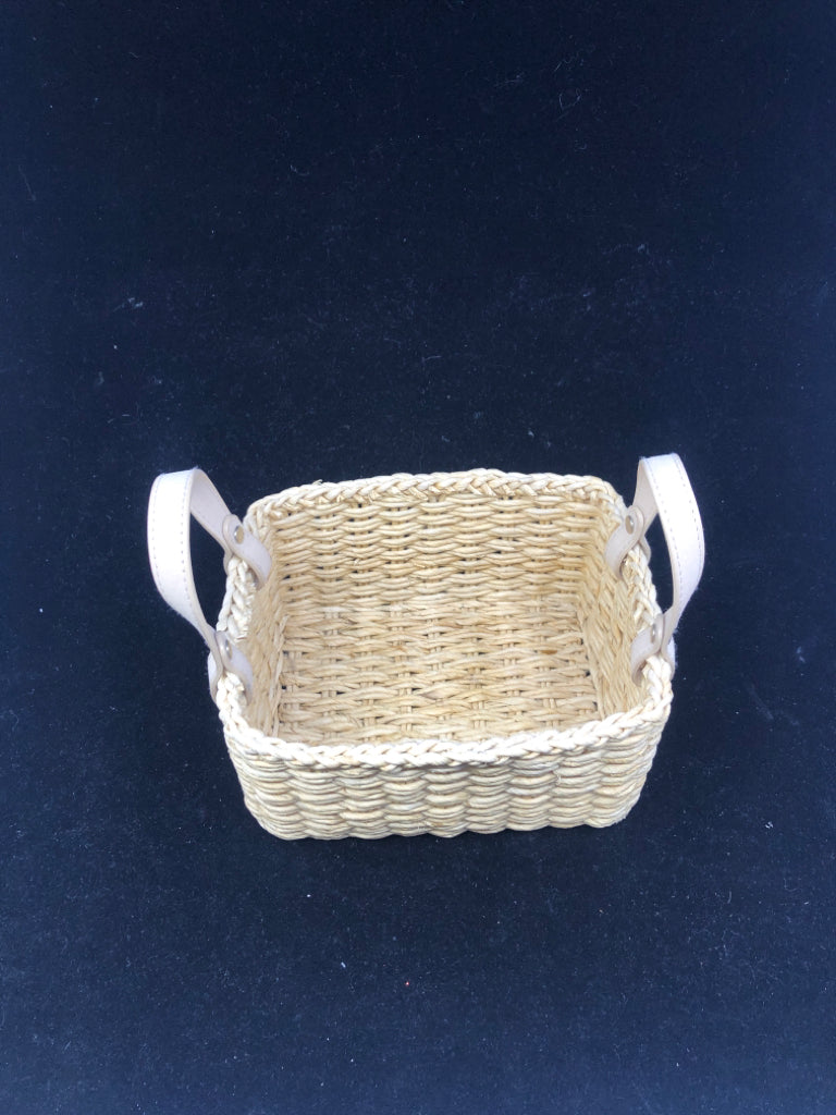 SMALL FLEXIBLE WOVEN BASKET W/ BEIGE FAUX LEATHER HANDLES.