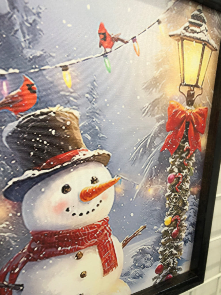 SNOWMAN IN FRONT OF LAMP PRINT IN DRK FRAME.