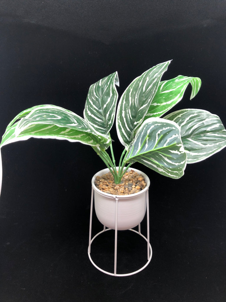 FAUX GREEN PLANT IN WHITE RAISED METAL PLANTER.