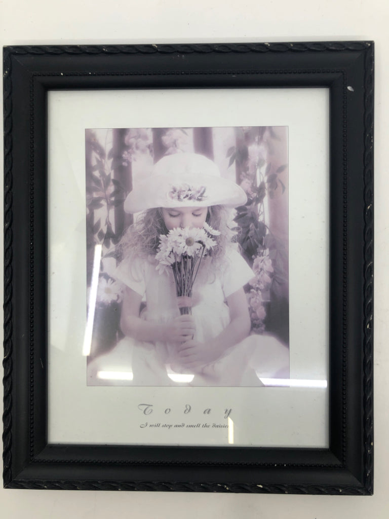 LITTLE GIRL SMELLING FLOWERS IN BLACK FRAME.