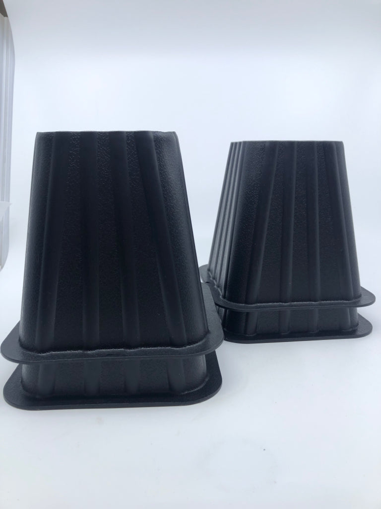 4 BLACK PLASTIC BED RISERS.