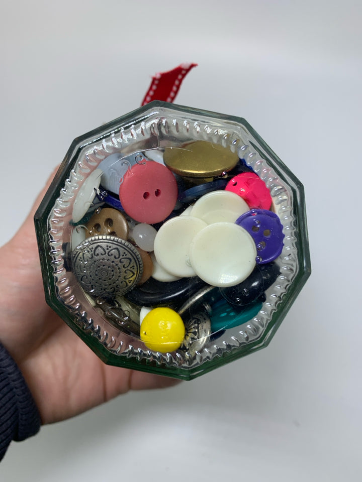 GLASS JAR FULL OF ASSORTED BUTTONS.