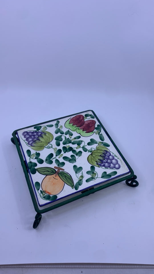 FRUIT PAINTED CERAMIC TRIVET ON GREEN METAL STAND.