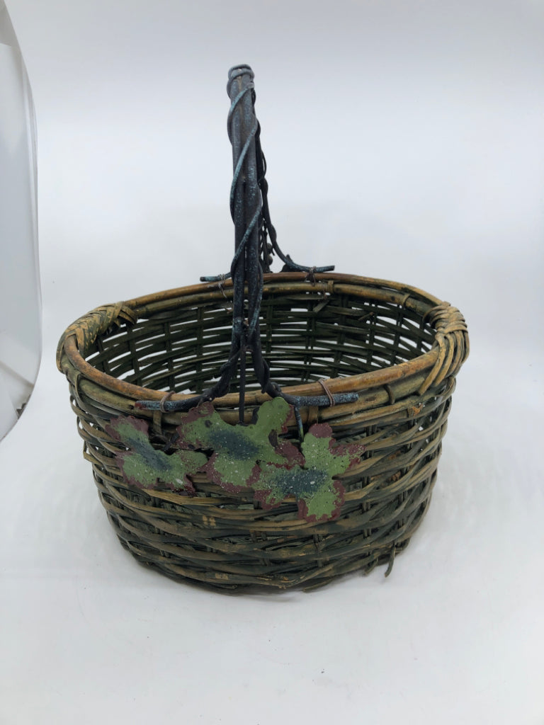 GREEN WOVEN BASKET W METAL HANDLE AND LEAVES.